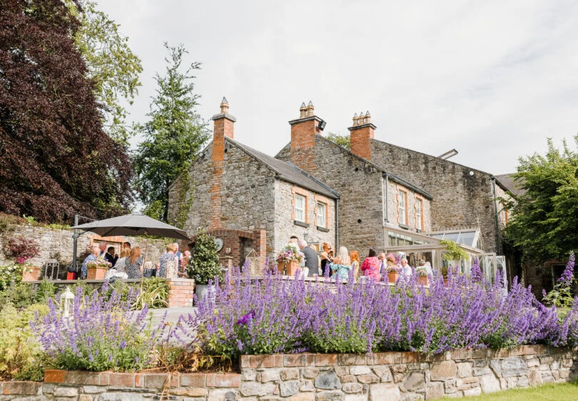 The stone Manor House at Ballymagarvey Village with its terrace and flowering garden