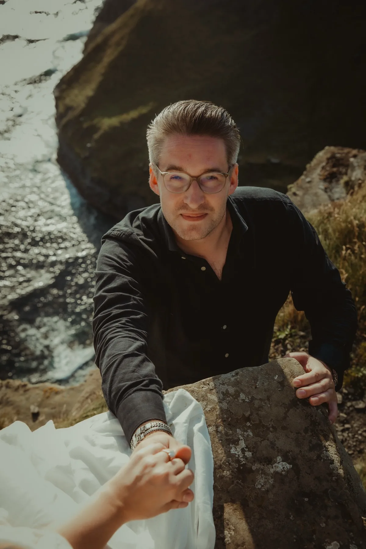 Oscar looking up while holding Shannon's hand on a rocky cliff path.